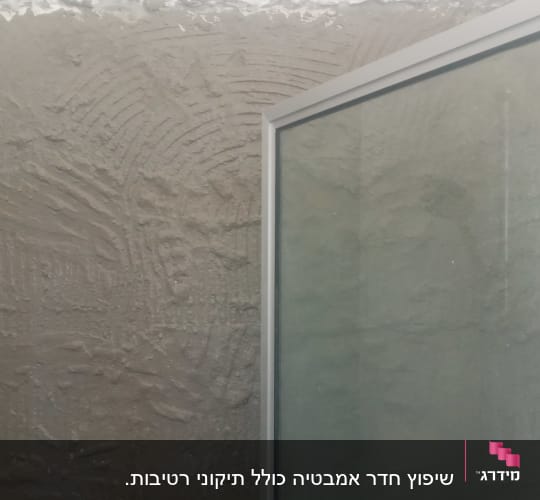 קיר עם טיח טרי ודלת זכוכית במקלחת